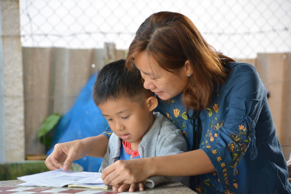 A foster parent reads with her son in Thailand